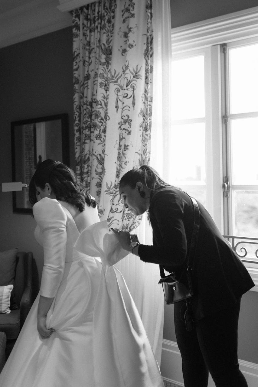 Carol Pires ajustando o laço do vestido da noiva